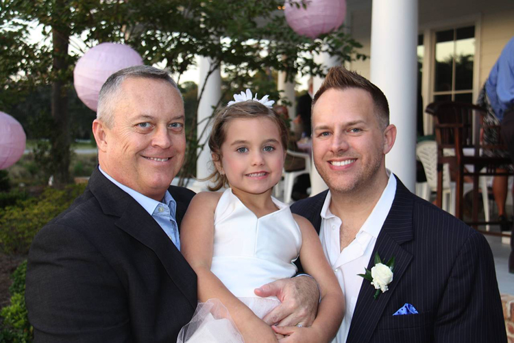 Jeff Littlefield, left, and his husband Tommy Starling pose with their 5-year-old daughter, Carrigan Starling-Littlefield, at a friend's wedding in Pawley's Island, S.C.