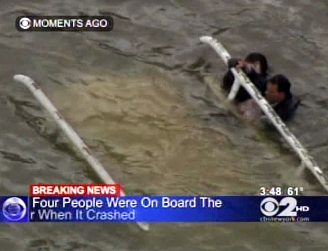 In this frame grab image taken from WCBS-TV, survivors cling to the bottom of a helicopter after it inverted following a crash into the East River in New York today.