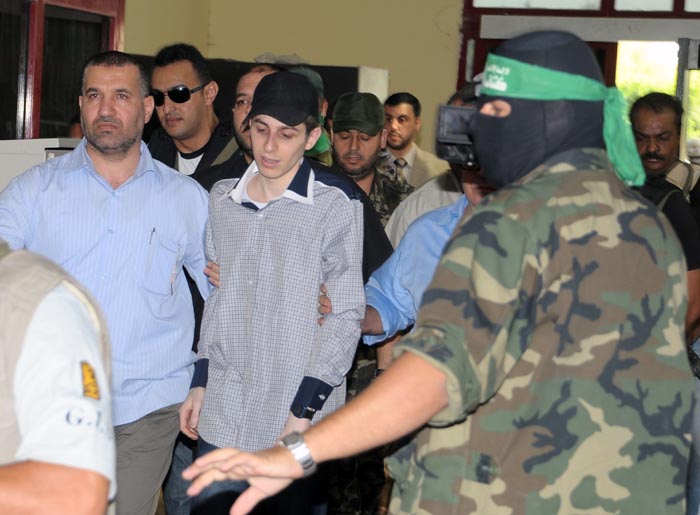 Looking dazed, thin and pale, Israeli soldier Gilad Schalit, center, is escorted by members of Hamas and the Egyptian mediators who helped arrange the tank crewman's release after more than five years in captivity.