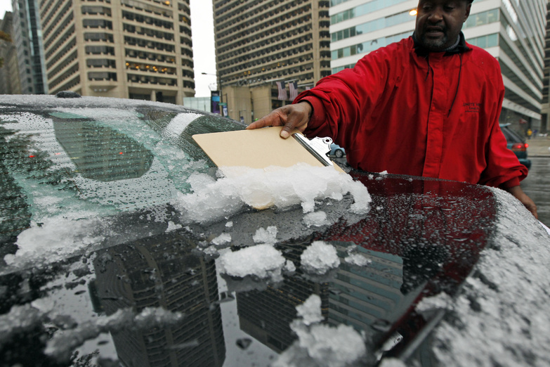 A man uses a clipboard to scrape the snow off of the back of his car window today in Philadelphia. A classic nor'easter was chugging along up the East Coast and expected to dump anywhere from a dusting of snow to about 10 inches throughout the region starting today, a decidedly unseasonal date for a type of storm more associated with midwinter.