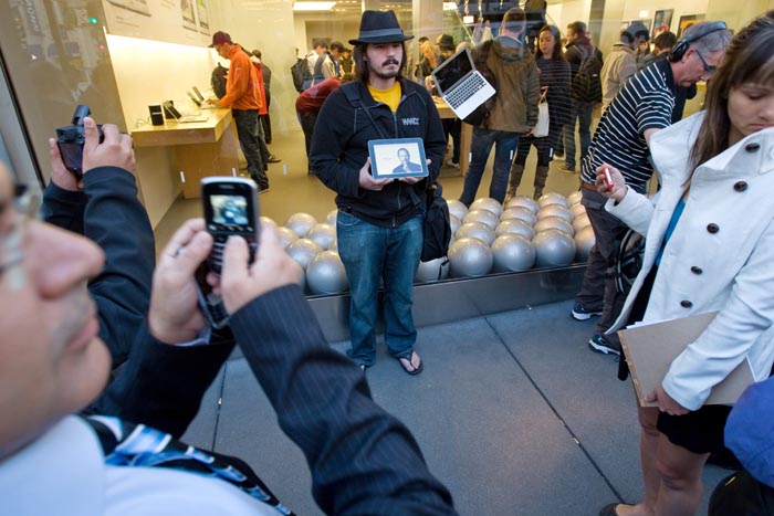 Steve Streza holds an iPad with a picture of Steve Jobs, as he and others gather outside an Apple store in San Francisco to mourn the Apple co-founder's death.