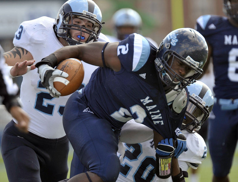 Maine running back Pushaun Brown is pulled down by Rhode Island's Michael Okunfolami, 20, and Doug Johnson in today's game at Orono. Brown ran for 103 yards and a TD in UMaine's 27-21 win.