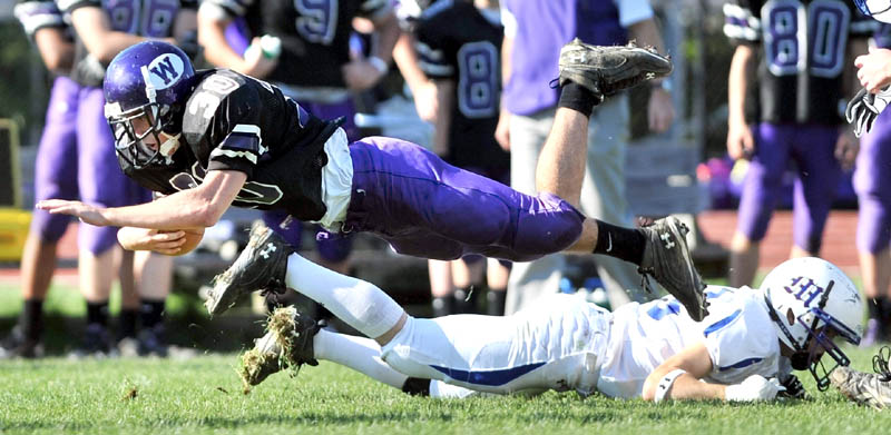 Staff photo by Michael G. Seamans Waterville high School running back Evan Greatorex, 30, dives for extra yardage over Madison high School defender Cody Soucier, 3, in the second quarter at Waterville Senior High School Saturday. Waterville defeated Madison 55-36.