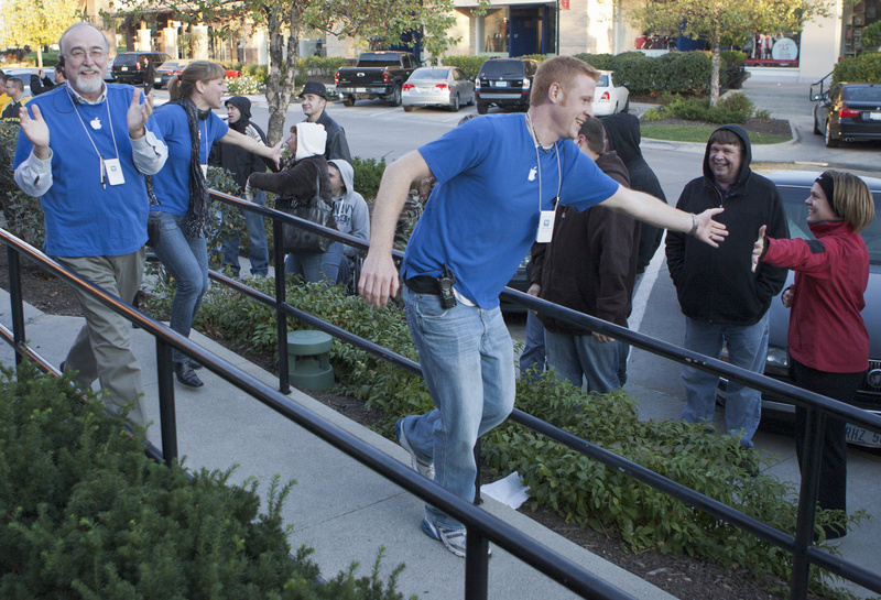 Apple store employees greet people waiting in line to buy the new iPhone 4S in Omaha, Neb., on Friday.