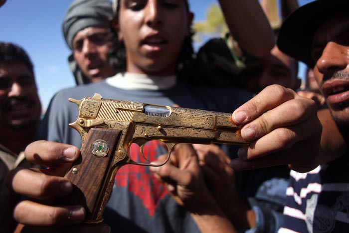 Mohammed al-Babi holds a golden pistol he says belonged to Moammar Gadhafi in Sirte, Libya.