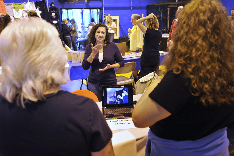 Brenda Schertz, an American Sign Language instructor at the University of Southern Maine, chats with visitors to her display at the festival, held in the Governor Baxter School for the Deaf gymnasium in Falmouth on Saturday.