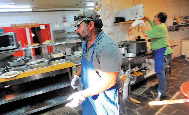Myao Perez hustles in the kitchen at Cancun Mexican Restaurant in Waterville as Hector Fuentes, back, prepares food for the dinner rush Tuesday.