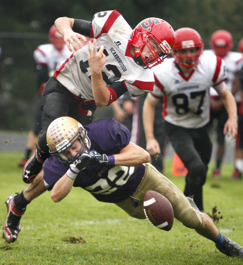 Donald Goodrich of Cheverus puts a hit on Scarborough quarterback Dillon Russo, causing a second-half fumble Saturday during the unbeaten Stags' 38-0 victory.