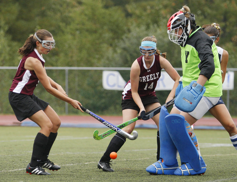 Yarmouth goalie Meaghan Gorman stands her ground Saturday as Helena McMonagle, left, and Freya Victory of Greely attempt to get the field hockey ball into the net.