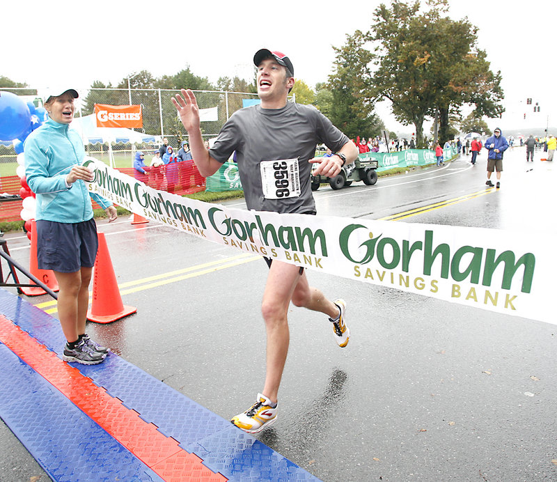 Maine Marathon winner Evan Graves of Caribou waves to supporters as he crosses the finish line Sunday. Graves ran the race in 2 hours, 36 minutes and 53 seconds. Waiting beyond the finish line were his wife and their daughter, Emma, who was born in June.