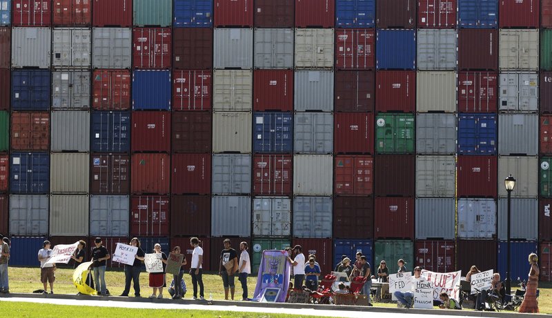 Demonstrators stand in front of the letters “IOU” spelled out on shipping containers across the street from the Federal Reserve Bank of Kansas City in Kansas City, Mo., on Friday.