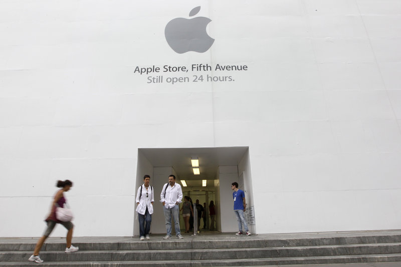 Customers stand outside the Apple flagship store on Fifth Avenue in New York. The computer and gadget maker is expected to announce a newer, more powerful version of its wildly popular smartphone today.