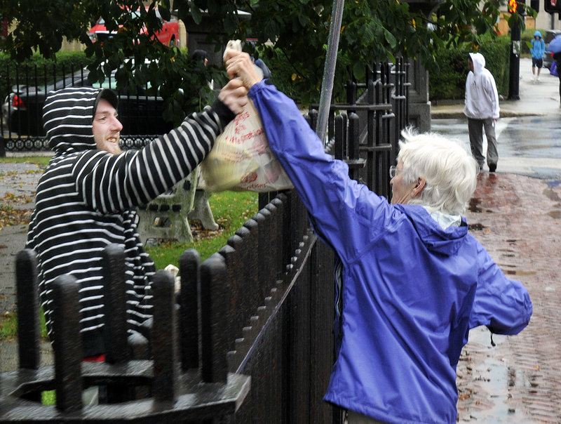 Constance Bloomfield hands bags of food over the fence at Lincoln Park in Portland to Chris Levesque, 22, of Biddeford, on Tuesday. Levesque is part of the group OccupyMaine, which had permission to set up tents in the park as part of its protest against Wall Street greed.
