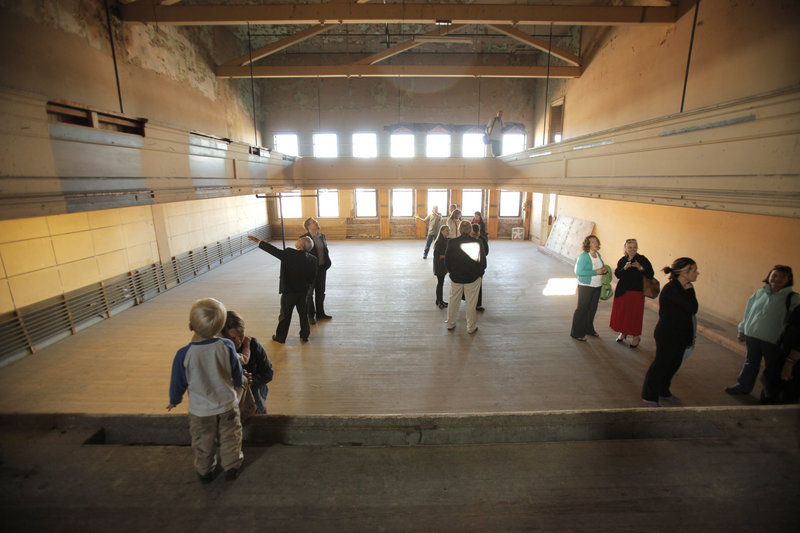 People tour the third floor of the former Renys store in Biddeford Wednesday where a small stage is located. The Reny family has donated the building on Main Street to Engine, a Biddeford nonprofit arts organization that wants to build an art presence downtown.