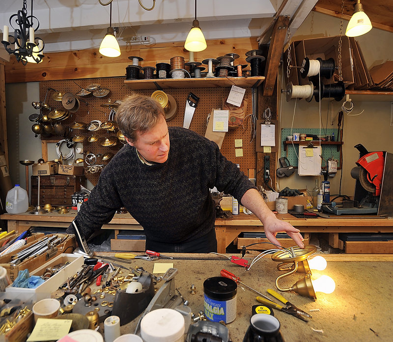 Burr Chase, a lightsmith at Decorum Specialty Hardware & Lighting in Falmouth, tests the electrical circuit on one of many custom-designed wall sconces he makes for the lighting and hardware store. Decorum used to be on Commercial Street in Portland, but closed in May 2010.