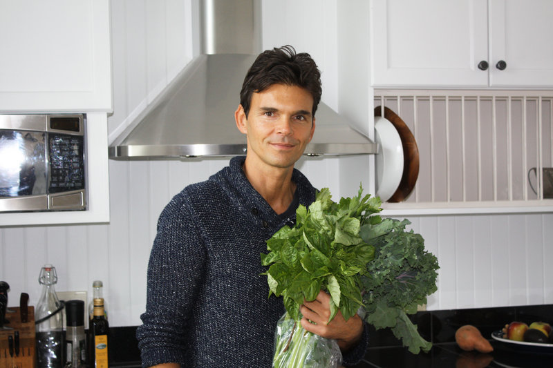 Holding fresh greens from Chase’s Daily, celebrity chef Matthew Kenney, who grew up in Searsmont, pauses for a photo in the kitchen of his Belfast home.