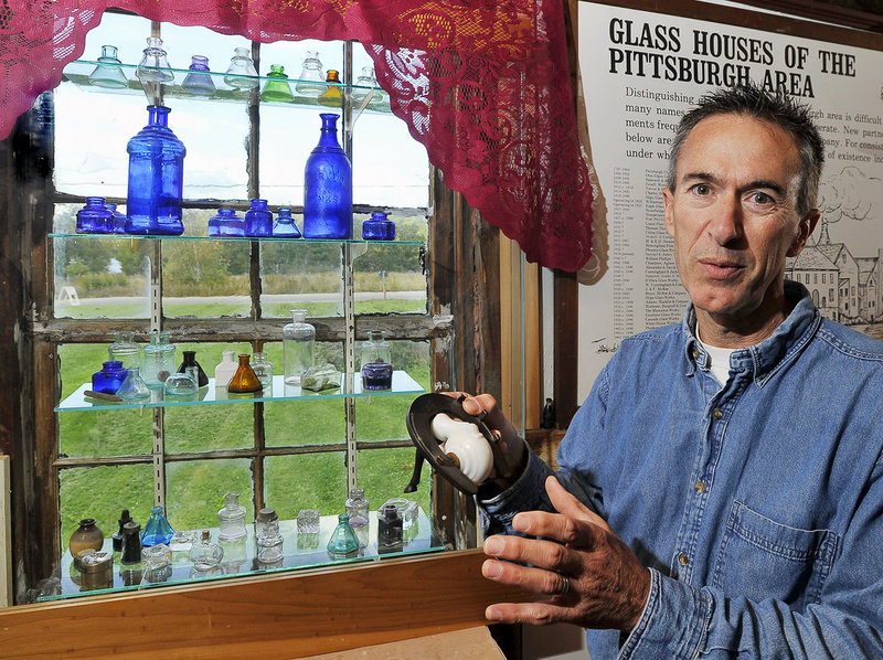 Walter Bannon shows one of the objects at his Maine Antique Bottle and Glass Museum in Bridgton – a snail-shaped inkwell made of milk glass that opens and closes to keep the ink from drying out. It is attached to a real horseshoe with a fabricated horse leg to keep it stable during use. In the window are old glass ink bottles of various shapes and colors that Bannon has found.