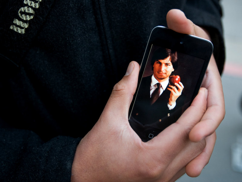 A dedicated Apple user holds an iPhone displaying an early picture of Steve Jobs during a gathering Wednesday at an Apple store in San Francisco.