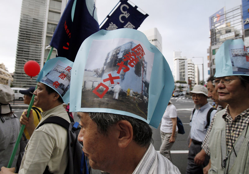 Anti-nuclear demonstrators, wearing paper hats bearing photographs of a damaged reactor at the Fukushima Dai-ichi nuclear power plant, march in Tokyo last month. The writing on the hats reads, “Stop nuclear power plants.”