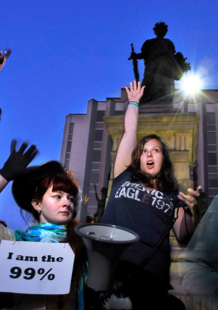 Holly Seeliger, left, and Rose Buckmore, both of Portland, raise their hands during an Occupy Maine assembly in Monument Square on Friday.