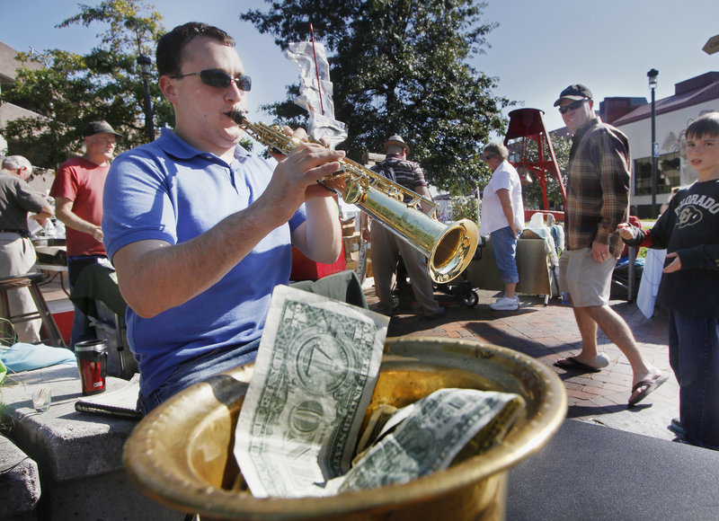 Jason Giacomazzo of Farmingdale plays soprano saxophone at Bell Buoy Park in Portland, hoping his musical talent will fill his busker's hat with tips.