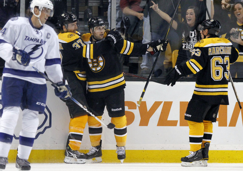 Rich Peverley of the Bruins, center, celebrates his goal with teammates Patrice Bergeron, left, and Brad Marchand as Vincent Lecavalier of the Lightning skates by in the third period.