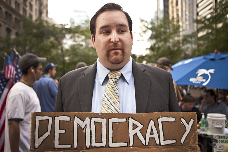 A man who asked to be identified only as “Dustin” holds a sign during the Occupy Wall Street protest in New York on Monday. The protest over class and wealth is entering its fourth week.