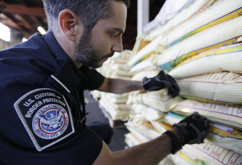 Mark Murphy, of U.S. Customs and Border Protection, examines bags of rice. Pest invasions have consequences such as higher grocery prices and substandard produce.