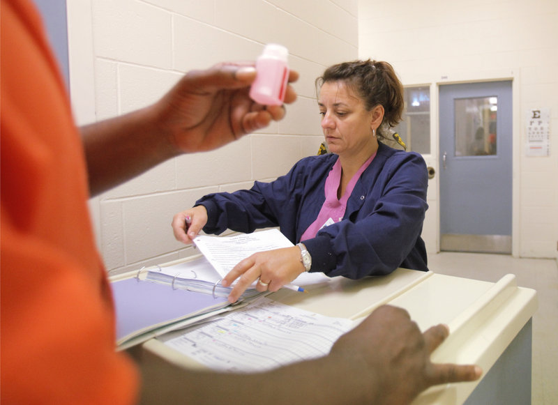 Carmen Mulholland, a nurse with Allied Resources, dispenses methadone to an inmate at the Penobscot County Jail in Bangor last month. Most of the 6,000 inmates who come through the jail in a year are taking some sort of medication, often for opiate addiction.