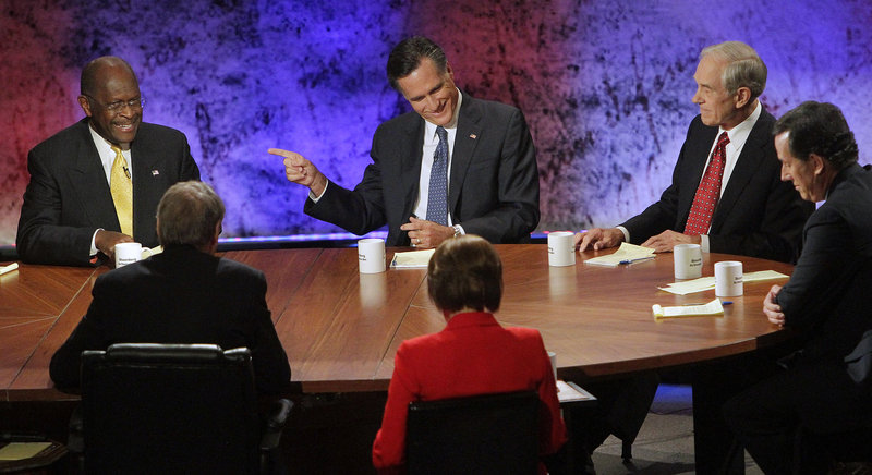 Former Massachusetts Gov. Mitt Romney points at businessman Herman Cain during a Republican presidential debate Tuesday night at Dartmouth College in Hanover, N.H. Rep. Ron Paul of Texas, right, looks on. The debate was the first to focus on the nation’s economy, and President Obama’s administration came under heavy fire.