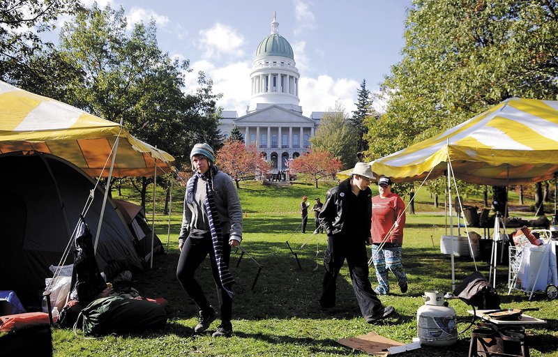 Occupy Augusta protesters walk Sunday between canopies covering tents at Capitol Park. The group plans to distribute statements on its key issues to passers-by, focusing on “those institutions that are keeping us in poverty,” a spokesman said.