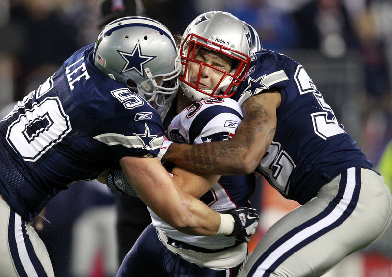Danny Woodhead of the Patriots takes a hit from Dallas’ Sean Lee, left, and Orlando Sandrick.