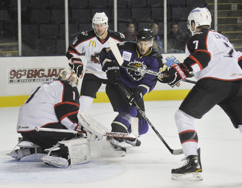 Justin Pogge of the Portland Pirates covers the puck after stopping a shot by Dwight King of Manchester.