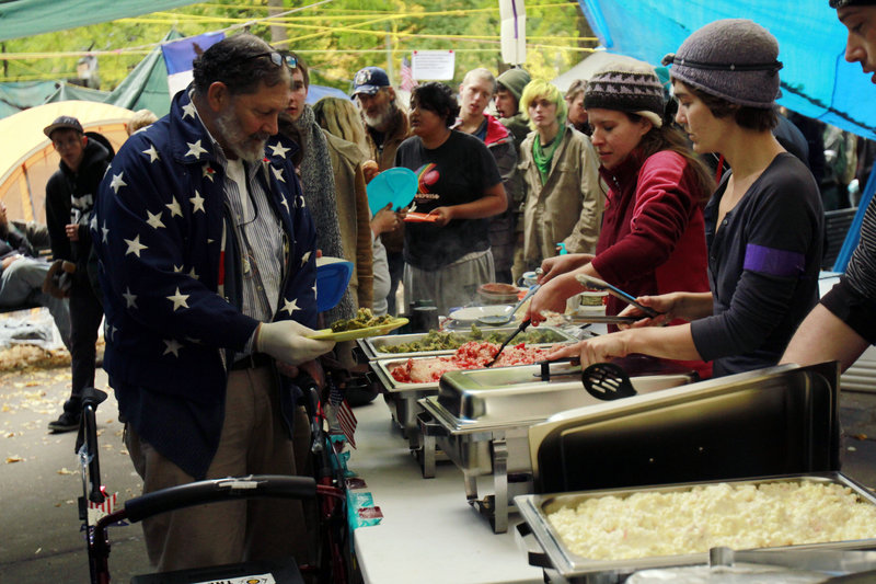 People line up for free lunch at Oregon’s Occupy Portland camp last week. Occupy camps nationwide are providing food and shelter to people who were already living outdoors.