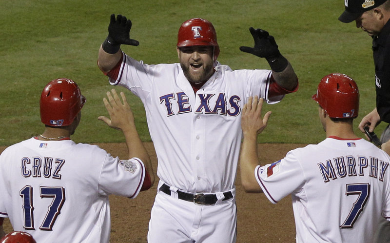 Mike Napoli of the Rangers is greeted by Nelson Cruz and David Murphy after he hit a three-run home run in the sixth inning of Game 4 of the World Series on Sunday night against St. Louis. Rangers starter Derrick Holland gave up two hits through 8 1⁄3 innings.