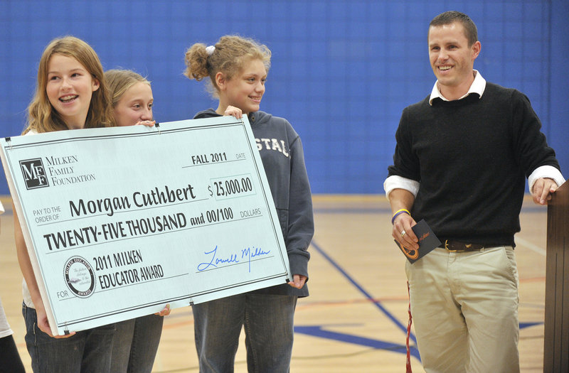 Middle school students hold a check made out to Cuthbert after his award was announced Monday.