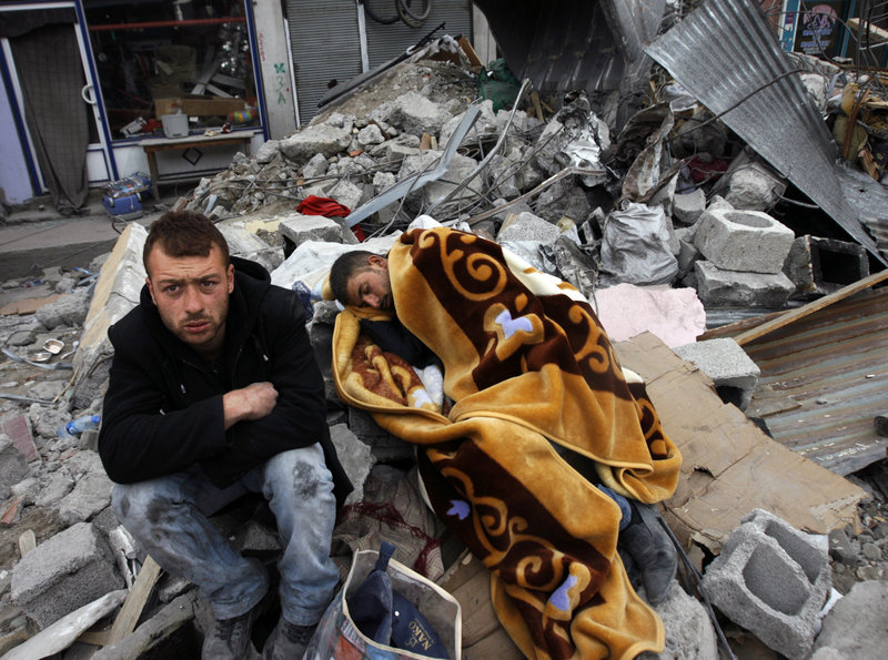 Turkish men rest as rescuers search for survivors in the debris of collapsed buildings in Ercis, eastern Turkey.