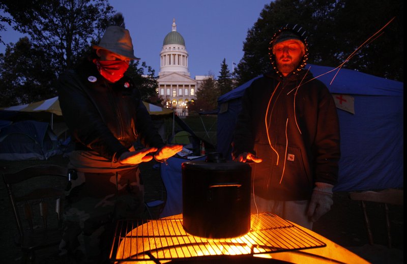 Occupy Maine protesters in Augusta warm their hands while brewing coffee on a fire pit at their encampment across from the State House early Friday morning. About 30 protesters in Augusta and dozens more in Portland camped out in near-freezing temperatures as they continued their protests against Wall Street excesses. The temperatures are likely to test their mettle again tonight as lows plummet to the mid-20s.