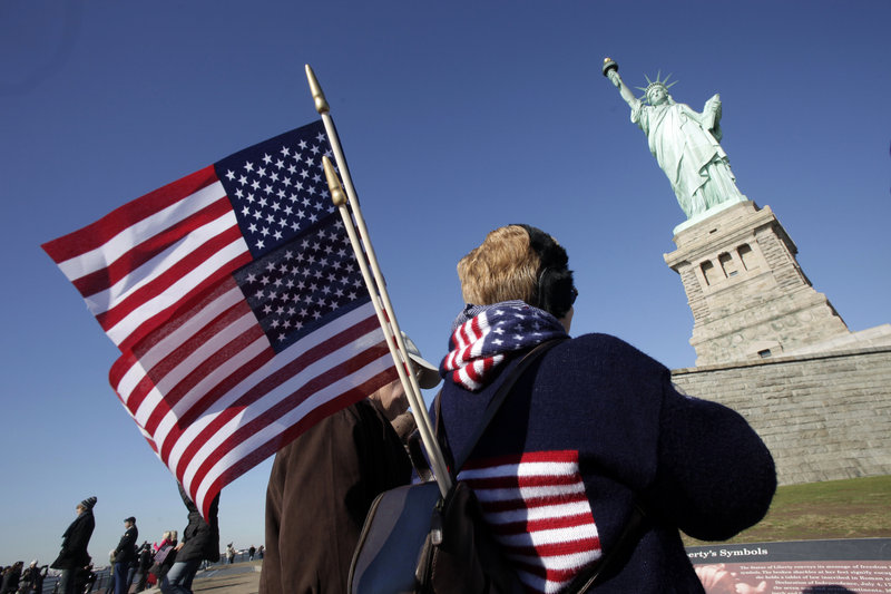 Donna Bodkins of Fisher, W.Va., carries American flags while visiting the Statue of Liberty on the landmark’s 125th anniversary Friday in New York. The statue was a gift from France and was dedicated on Oct. 28, 1886.