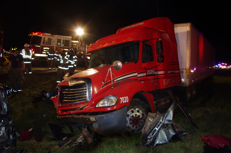 Firemen and police examine the wreckage of a fatal accident on a toll road near Bristol, Ind., on Thursday – caused when a packed minivan was hit from behind by a semi-trailer.