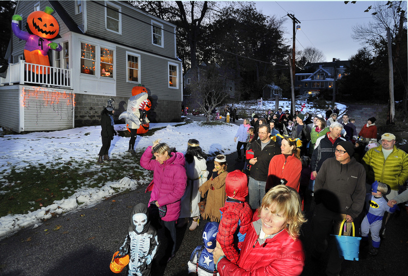 Costumed kids and parents pass the Halloween-themed home of John Taxter during the Falmouth Halloween Parade through the Falmouth Foreside Town Landing neighborhood Monday.