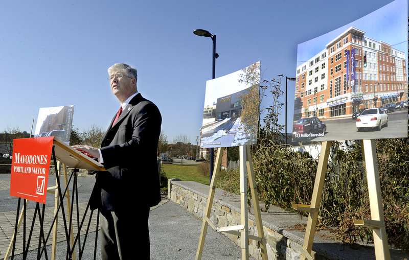 City Councilor and incumbent mayor Nicholas Mavodones speaks along the Bayside Trail in Portland Wednesday. Photos of recent development projects by law firm Pierce Atwood, left, the Portland International Jetport, center, and Hampton Inn are on display behind him.