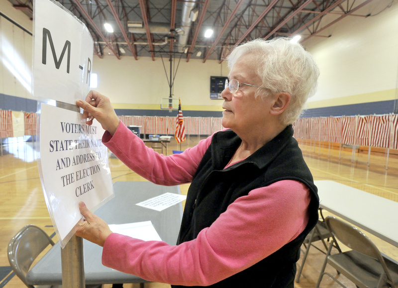 Falmouth deputy warden Sandra Davis tapes up instructions for voters Monday as she readies the polling place at Falmouth High School for today’s elections.