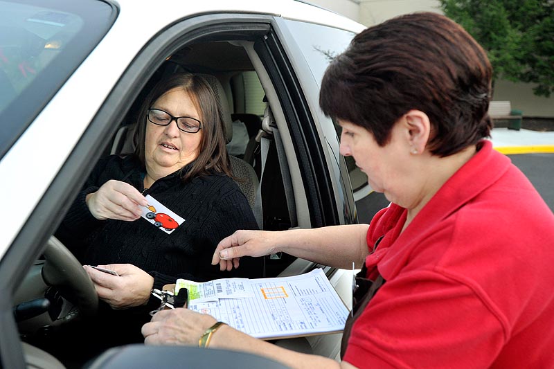 Photo by John Ewing/staff photographer... Tuesday, November 22, 2011. Hannaford's is launching a new service, Hannaford to Go, which allows shoppers to order groceries online and then pick their completed order at the store and into their car. "To Go" shopper Deb Haines hands a credit card to pay for her order to Hannaford associate Charlene DeLisle.