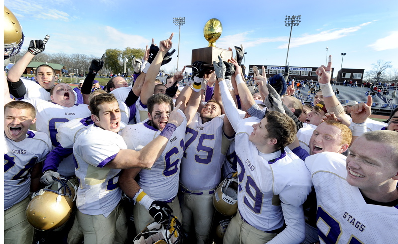 Cheverus players hoist the Gold Ball for the second year in a row after beating Lawrence 49-7 to win the Class A football state championship.