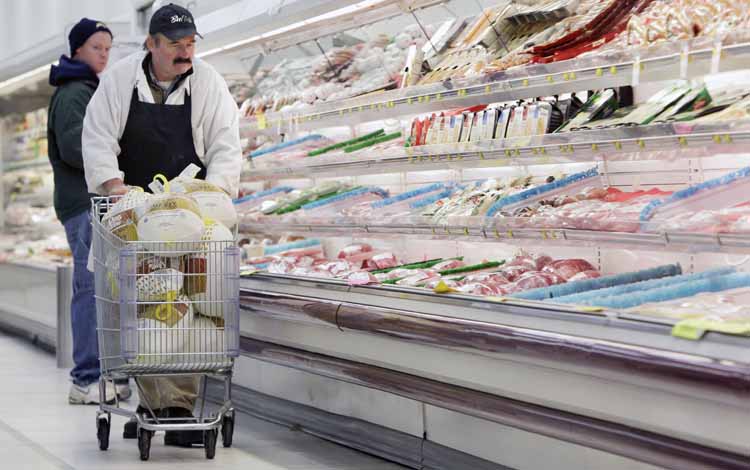 Dennis Sheehan, meat manager, pushes a shopping cart full of turkeys for stocking at Pixley's Shurfine grocery store in Akron, N.Y., today.