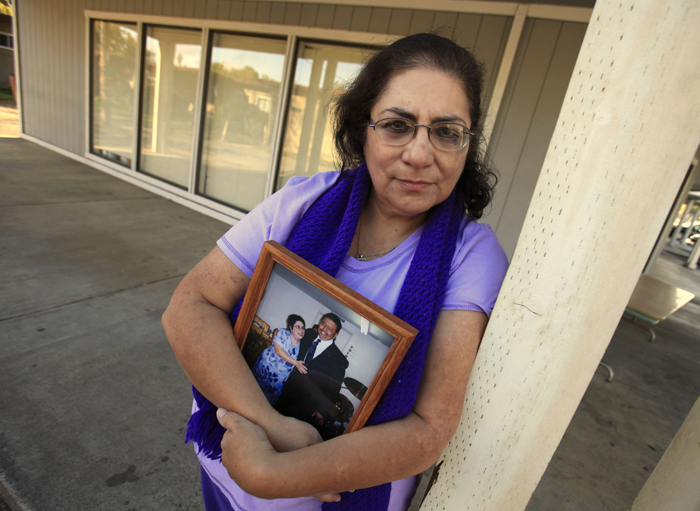 Karen Carrisosa holds a photo of her and her husband Larry, at the site where he was killed in Sacramento, Calif. Carrisosa became concerned when officials found a Facebook posting from Corcoran State Prison inmate Fredrick Garner who is serving a 22-year, involuntary manslaughter sentence for killing Larry 11 years ago.