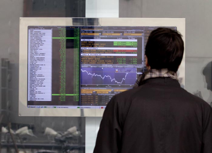 A man checks stock indexes on a screen of a bank in Milan, Italy, today. For the second time in as many market days, Italy paid sharply higher borrowing rates in an auction today, as investors continued to pressure the eurozone's third largest economy to come up with reforms urgently.