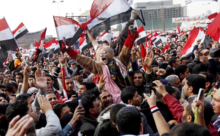 Protesters, including a man holding tear gas cannisters, chant slogans and wave national flags during a rally in Tahrir Square in Cairo today. Tens of thousands of protesters chanting, "Leave, leave!" are rapidly filling up Cairo's Tahrir Square in what promises to be a massive demonstration to force Egypt's ruling military council to yield power. The rally is dubbed by organizers as "The Last Chance Million-Man Protest," and comes one day after the military offered an apology for the killing of nearly 40 protesters in clashes on side streets near Tahrir over the last week.