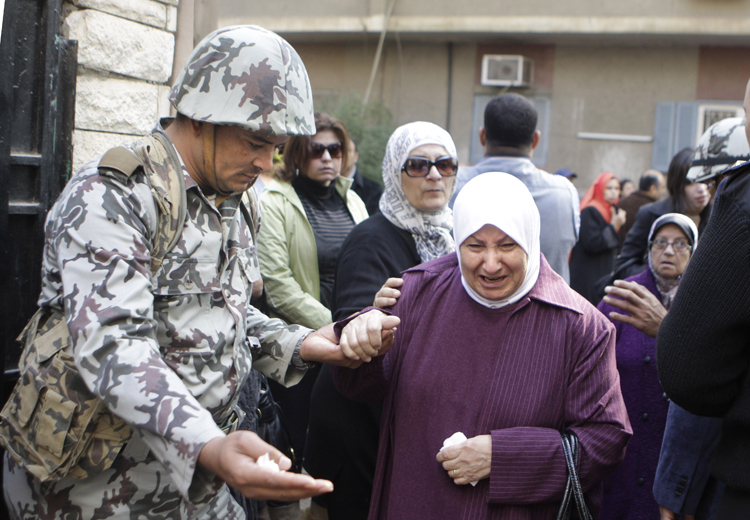 An Egyptian woman is helped by a soldier as she enters a polling center in Cairo today.Voting began today in Egypt's first parliamentary elections since longtime authoritarian leader Hosni Mubarak was ousted in a popular uprising nine months ago.
